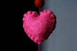 Magenta heart stitched and felted, hanging on a thread.