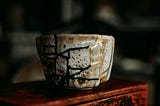 A broken cup that has been meticulously put together by the Kintsugi technique that has gold hold the broken pieces together, making the result even more beautiful than the original.