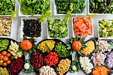 An array of colorful vegetables and other foods from a salad bar.