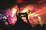 A person holding up a phone to record a concert