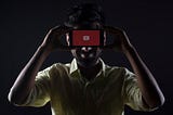 A man holds a smartphone showing the YouTube logo up to his face