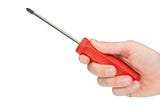 a hand holding a red-handled screwdriver against a white background