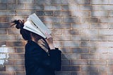A girl covering her face with a book