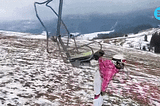 Ladies handed by her backpack to a moving chair lift