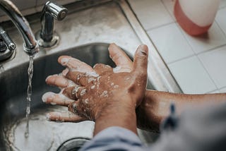A person who washes their hands thoroughly in a sink.
