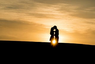 man and woman embracing at sunset, illustrative of love