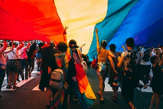 People underneath a large pride flag