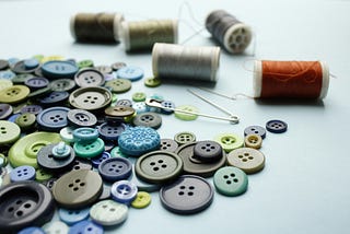 Image of assorted buttons and spools of thread in a pile.