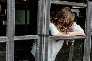 Young teenage girl leaning on what looks like a window frame