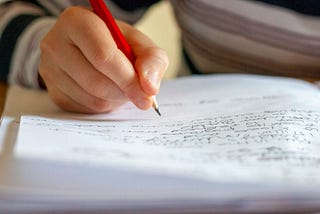 Person writes by hand with pencil in notebook