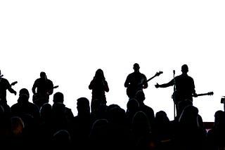 A musical band performing on stage in silhouette.