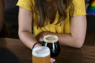 Photo of a young woman with long dark hair drinking a beer