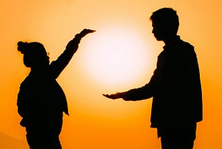 a woman and man framing the sun with their hands