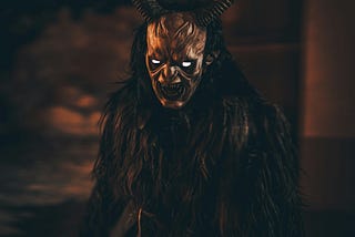 A demon covered in gorilla-like fur, with white-glowing eyes, and long curving horns. Pointed teeth are revealed in a snarling mouth.