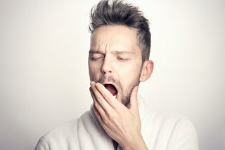 A man in a white background yawning because he has to work.
