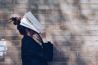 A girl covering her face with a book