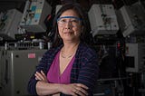 Joannie Chin poses in the lab wearing safety goggles, with her arms crossed.