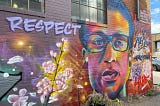 A colorful mural of Elijah McClain by #SprayHisName with the word RESPECT and flowers.