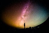 A man silhouetted in front of space — photo courtesy of Greg Rakozy on Unsplash