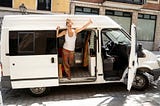 Female vanlifer in a white van giving the thumbs up