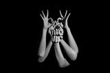 A group of hands reaching up in the air, forming different shapes with the fingers. A black and white photo