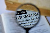A picture of a magnifying glass magnifying the word “Grammar” in a book