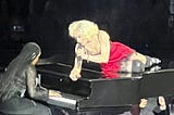 Madonna lays across a piano singing, while her daughter plays