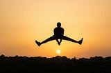A person jumps for joy, apparently rising over the sun