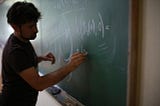 Man writing mathematics on a blackboard.