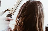 In a hair salon, a woman’s hair is curled.