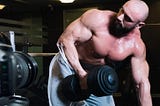 Shirtless guy with big muscles lifting weights in front of a video camera