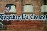 A brick wall with the words “Together We Create” painted in large letters. Photo by <a href=”https://unsplash.com/@bamagal?utm_content=creditCopyText&utm_medium=referral&utm_source=unsplash">"My Life Through A Lens”</a> on <a href=”https://unsplash.com/photos/white-and-black-together-we-create-graffiti-wall-decor-bq31L0jQAjU?utm_content=creditCopyText&utm_medium=referral&utm_source=unsplash">Unsplash</a>