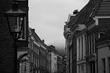 Black and white photo of a street at the end of which a shiny dome can be seen.