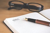 Eyeglasses, fountain pen, and an open journal with the heading of “Notes” written at the top. Photo by <a href=”https://unsplash.com/@dtravisphd?utm_content=creditCopyText&utm_medium=referral&utm_source=unsplash">David Travis</a> on <a href=”https://unsplash.com/photos/brown-fountain-pen-on-notebook-5bYxXawHOQg?utm_content=creditCopyText&utm_medium=referral&utm_source=unsplash">Unsplash</a>