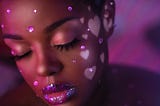 A Black woman, eyes closed with a short afro, with pink rhinestones on her face, white hearts pressed on her cheeks and sparkly pink lipstick. Yummy.