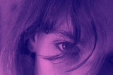 Close-up of two eyes,through messy hair. Photo edited in a purple tint.