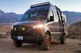 Mercedes Sprinter camper 4x4 in grey with front foglights on with mountains in the background