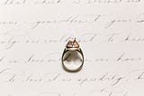 Diamond ring on top of a white piece of paper with handwriting.
