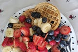 Circular toaster waffles topped with a heap of mixed fruit