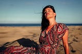 Woman wearing a beautiful dress while sunbathing at a Spanish beach. How moving to Spain changed my approach to health, fitness, and happiness