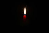 Flame of red candle against black background