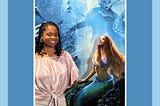 A Black woman posing with The Little Mermaid (2023) movie poster.