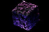 A textured purple cube resembling high technology against a very dark background.