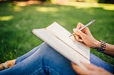 A person taking notes while sitting on the grass