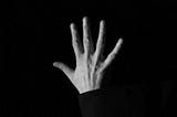 A black-and-white image of a hand with its fingers splayed representing the five lessons I have learned during my second month writing for Medium