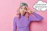 Young woman with pink hair making a silly face and a cartoon koala sleep mask on her head — throwing a peace sign