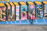 A young man poses in front of detailed, elaborate graffiti spelling out ‘Chicago.’