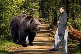 A man and a bear are standing in the woods