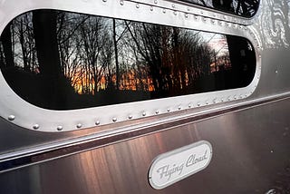 reflection of sunrise in my airstream flying cloud window