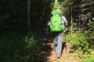 Man with a big pack sack hiking in the woods